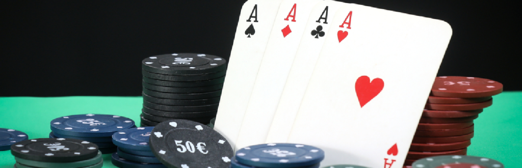 Poker chips and four aces on a poker table.