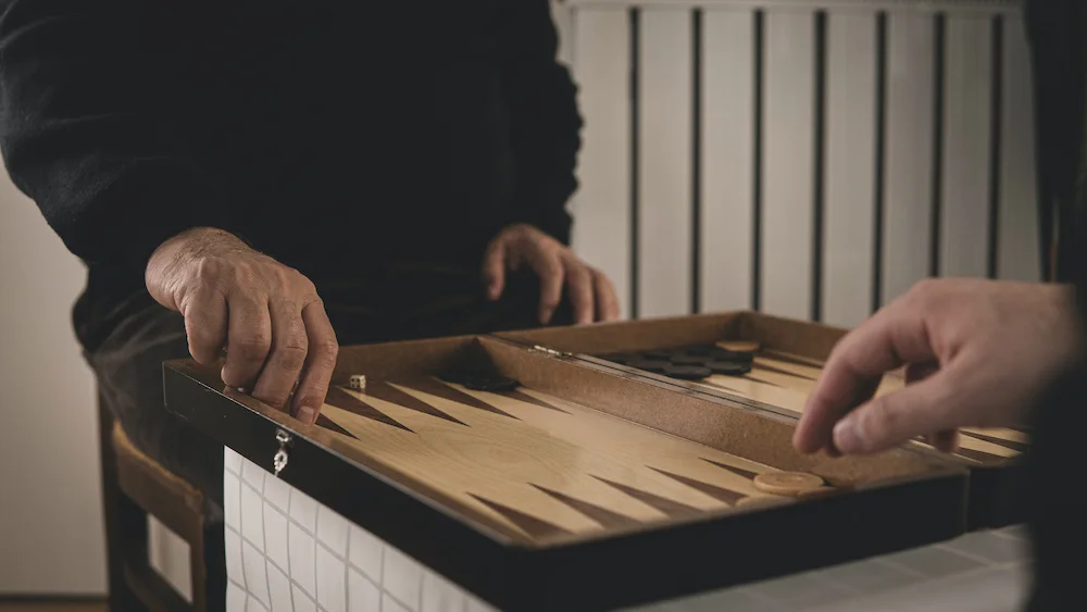 Two individuals engaged in a game of backgammon